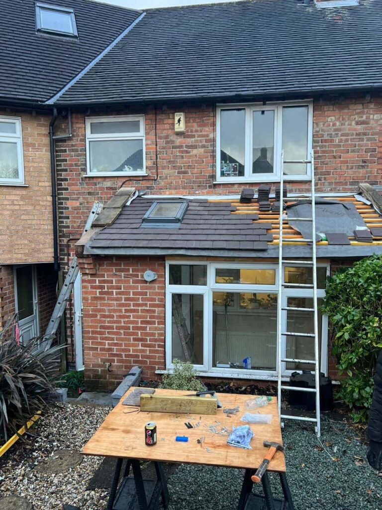 This is a photo of a roof extension that is having new roof tiles installed. This is a photo taken from the roof ridge looking down a tiled pitched roof on to a flat roof. Works carried out by Knightsbridge Roofing Repairs