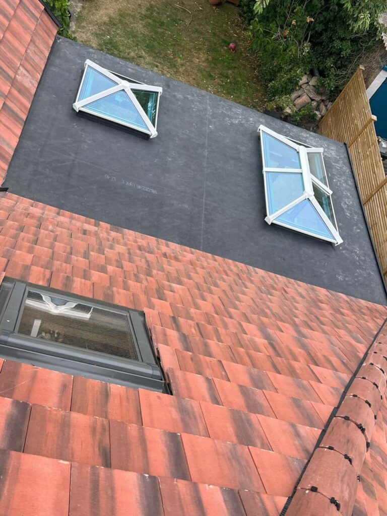 This is a photo taken from the roof ridge looking down a tiled pitched roof on to a flat roof. Works carried out by Knightsbridge Roofing Repairs